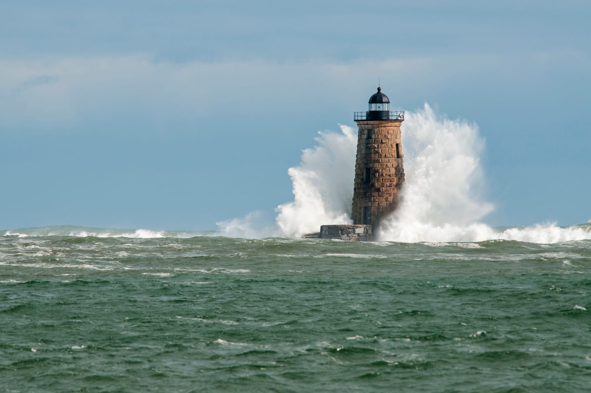 Photo of lighthouse being struck by an ocean wave